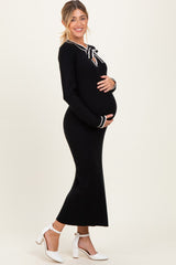 woman wearing a black long sleeve maternity dress with a tie neckline and ribbed texture, showcasing her baby bump
