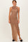 woman wearing a taupe sleeveless maxi dress with ruching and a side slit, styled with black heels