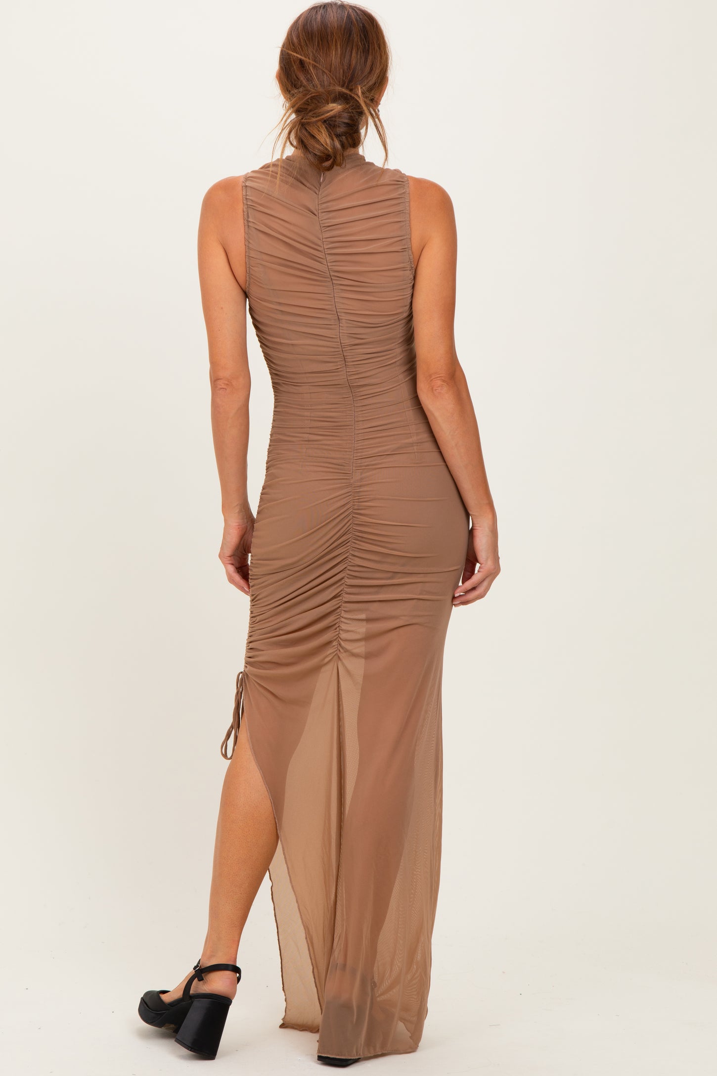 woman wearing a beige sleeveless maxi dress with ruching details and a side slit, shown from the back