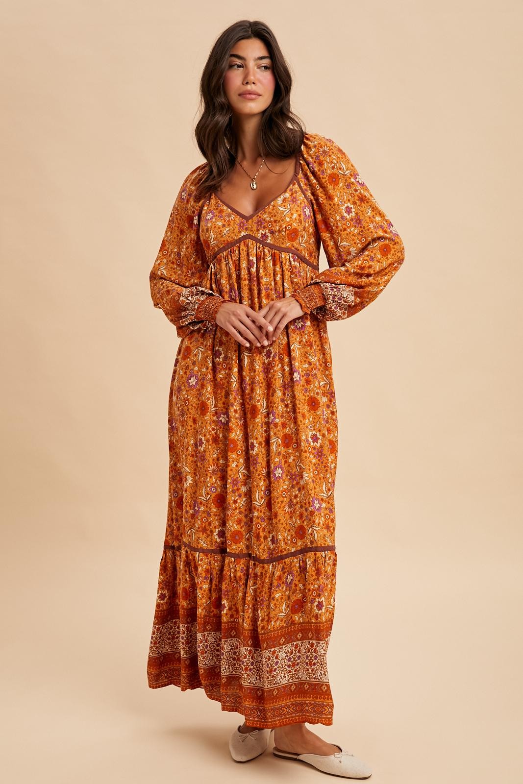 woman wearing a long orange floral maxi dress with puff sleeves and a tiered skirt
