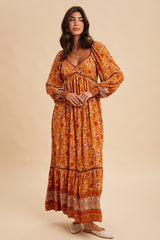 woman wearing a long orange floral maxi dress with puff sleeves and a tiered skirt