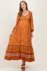 woman wearing a rust floral maternity maxi dress with long sleeves and a baby bump visible