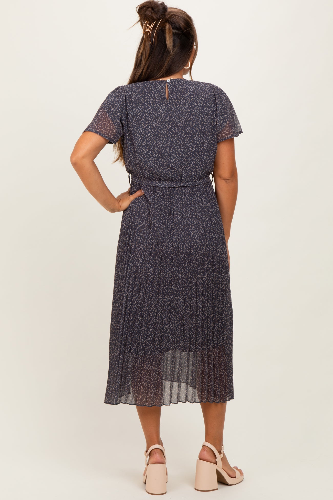 woman wearing a dark floral maternity dress with short sleeves and a tie waist, viewing from the back