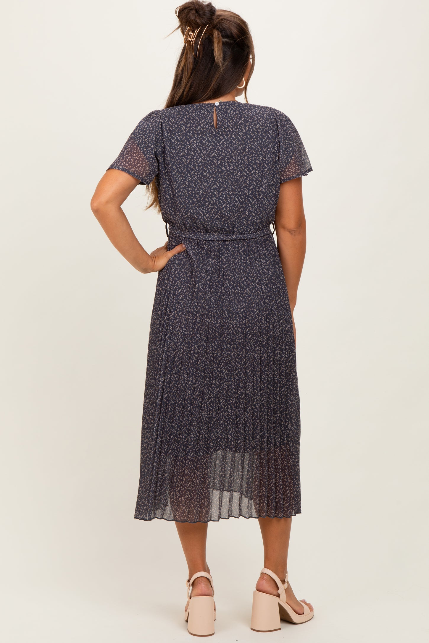 woman wearing a dark floral maternity dress with short sleeves and a tie waist, viewing from the back