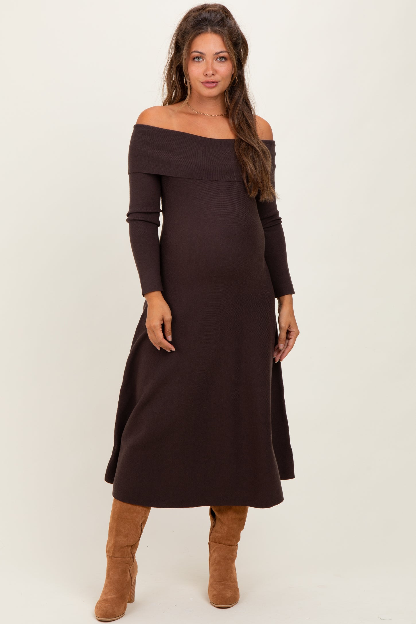 woman wearing a dark brown off-the-shoulder maternity dress and showing her baby bump
