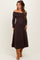 woman wearing a chocolate brown off-shoulder maternity dress with long sleeves and a visible baby bump