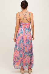 woman wearing a colorful floral maxi dress with crisscross straps and a smocked waist, seen from the back