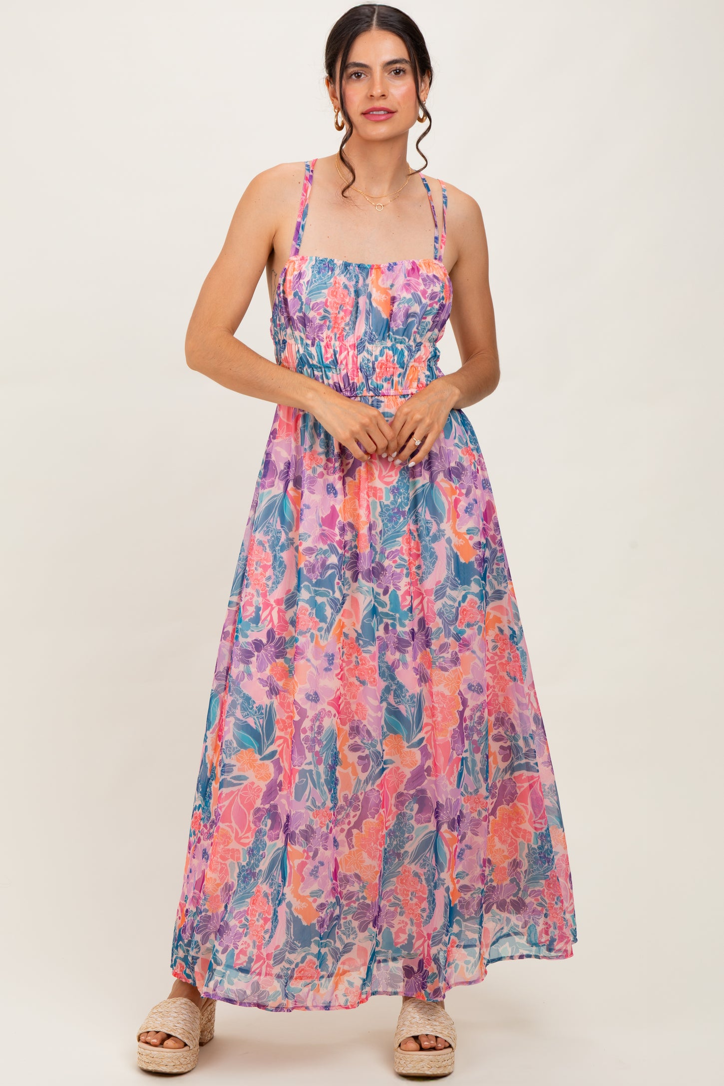 woman wearing a floral maxi dress with a smocked bodice and spaghetti straps, standing against a light background