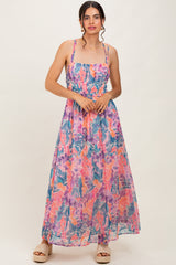 woman wearing a floral maxi dress with a smocked bodice and spaghetti straps, standing against a light background