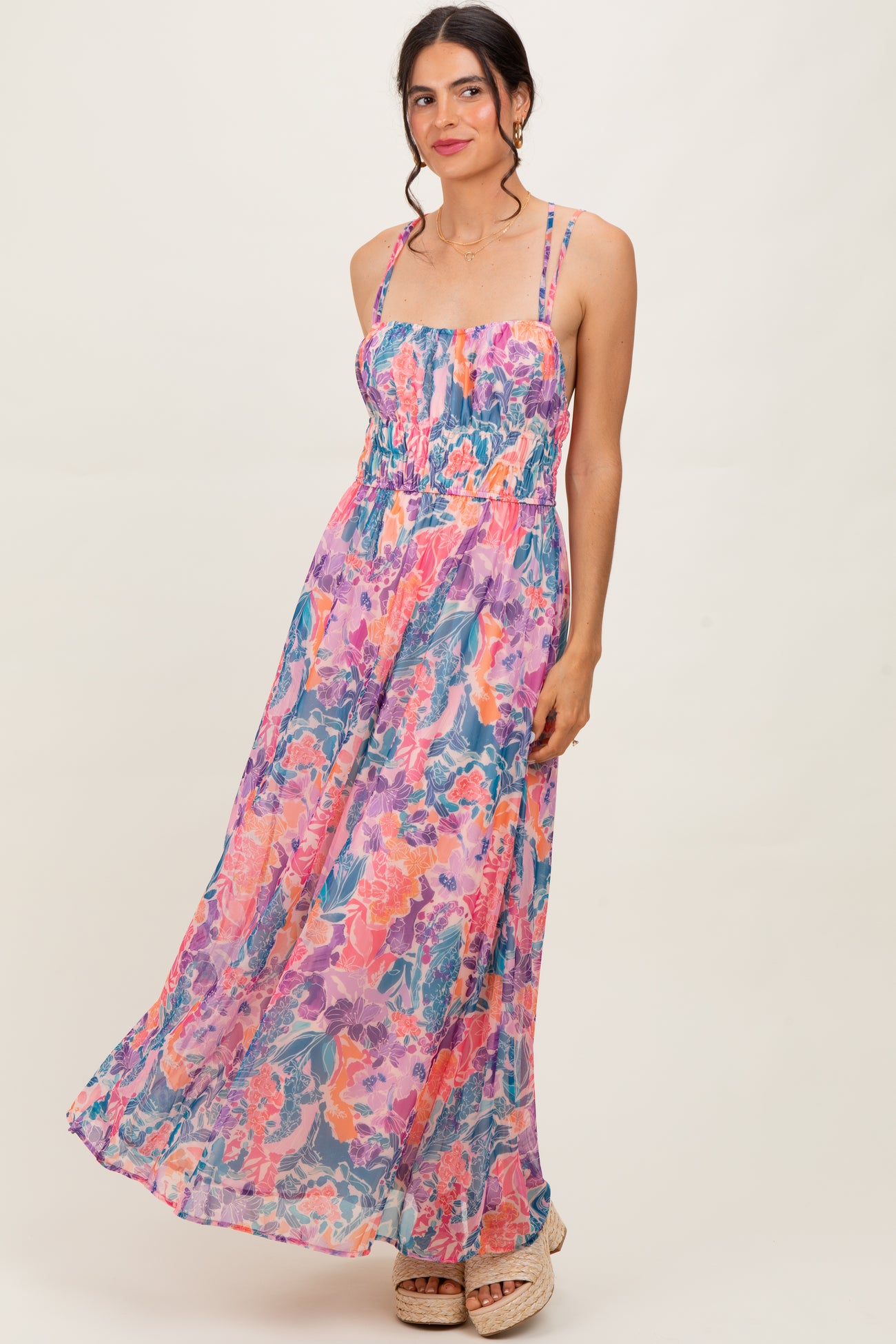 woman wearing a colorful floral maxi dress with spaghetti straps and a smocked bodice