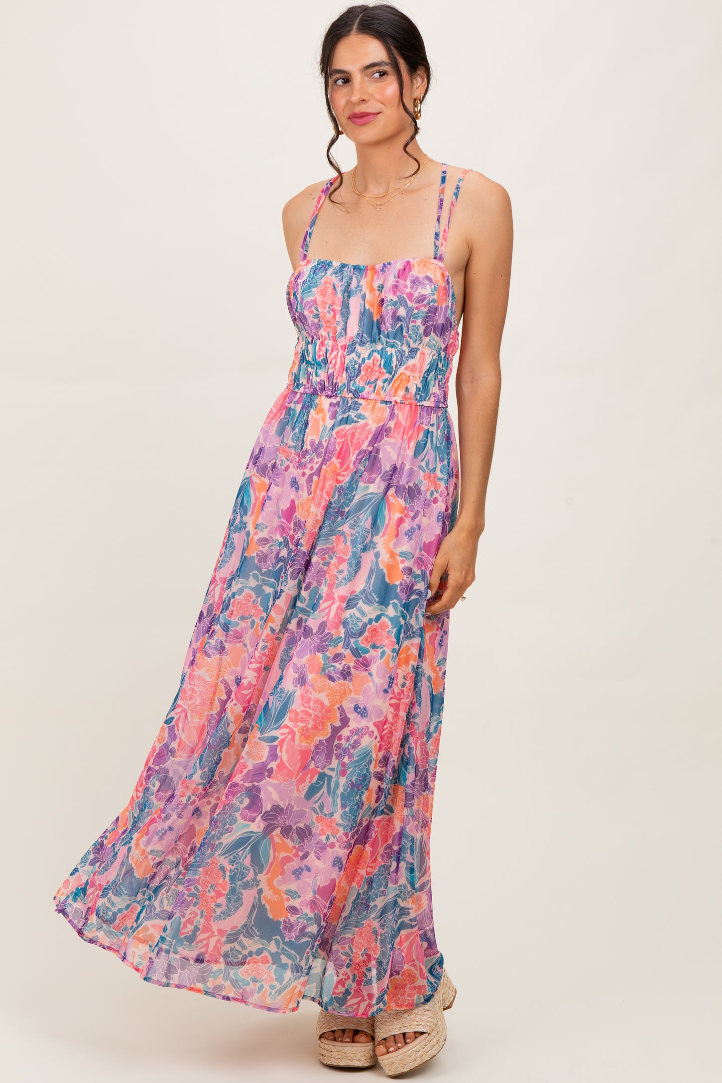 woman wearing a colorful floral maxi dress with spaghetti straps and a smocked bodice
