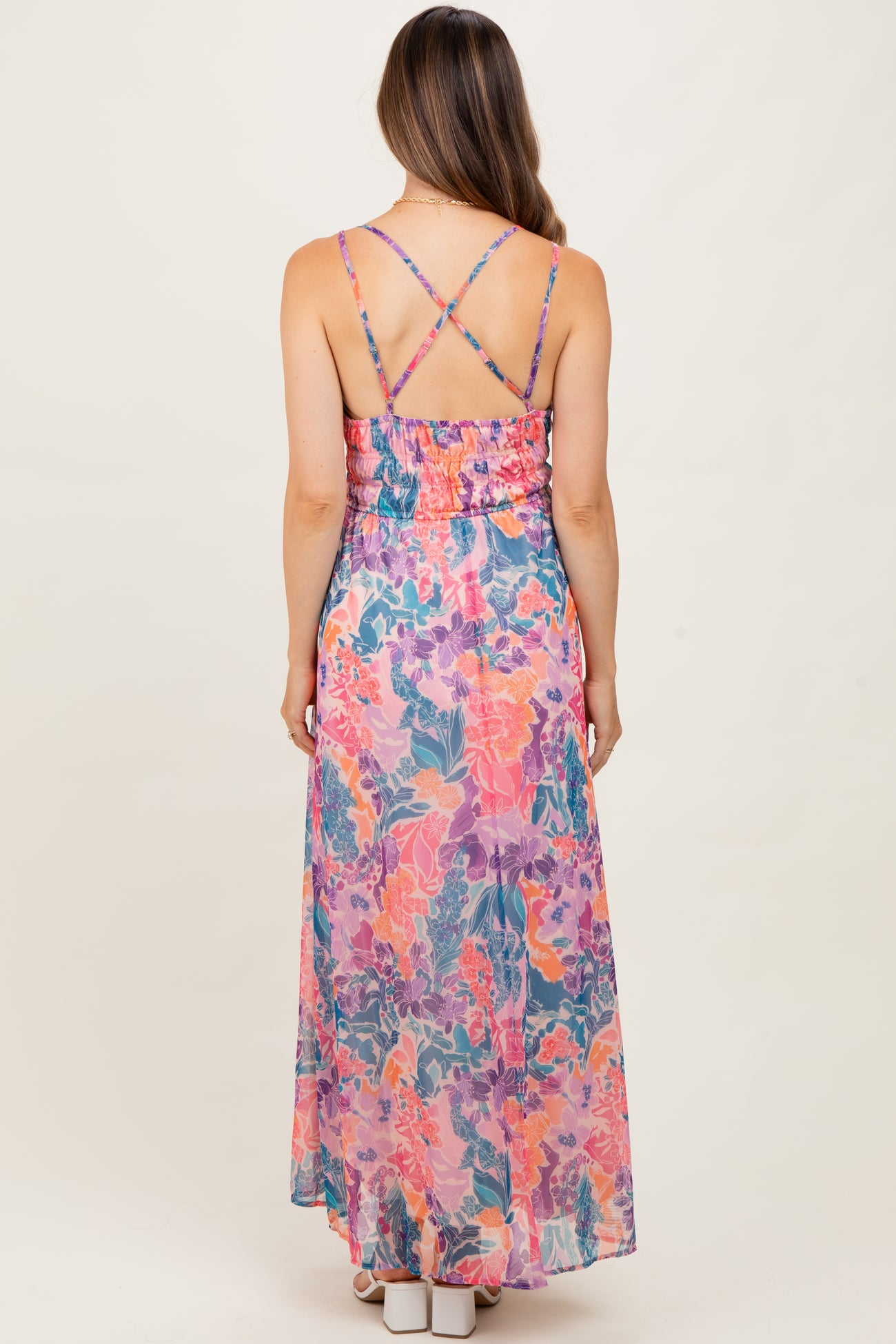 woman wearing a colorful floral maternity maxi dress with adjustable crisscross straps and a smocked back