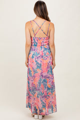 woman wearing a colorful floral maternity maxi dress with adjustable crisscross straps and a smocked back