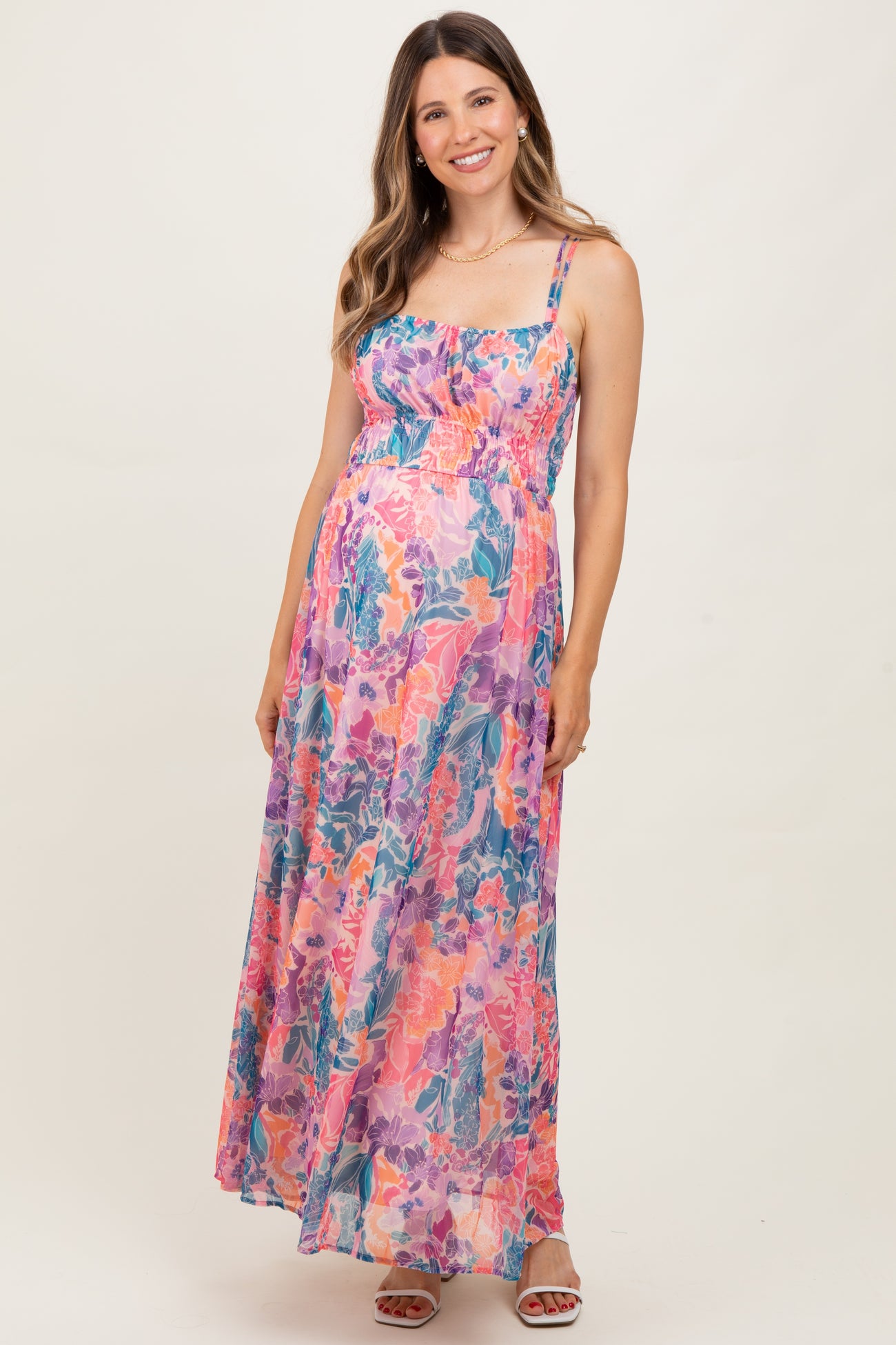 woman wearing a flowing floral maternity maxi dress with adjustable straps and holding her baby bump