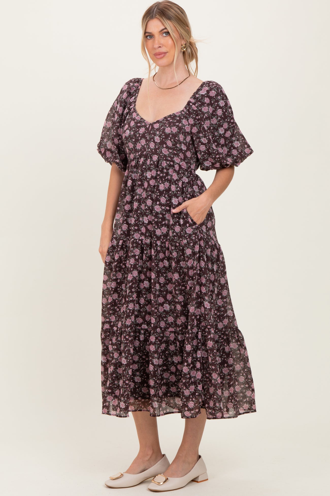woman wearing a black floral maxi dress with short puff sleeves and pockets