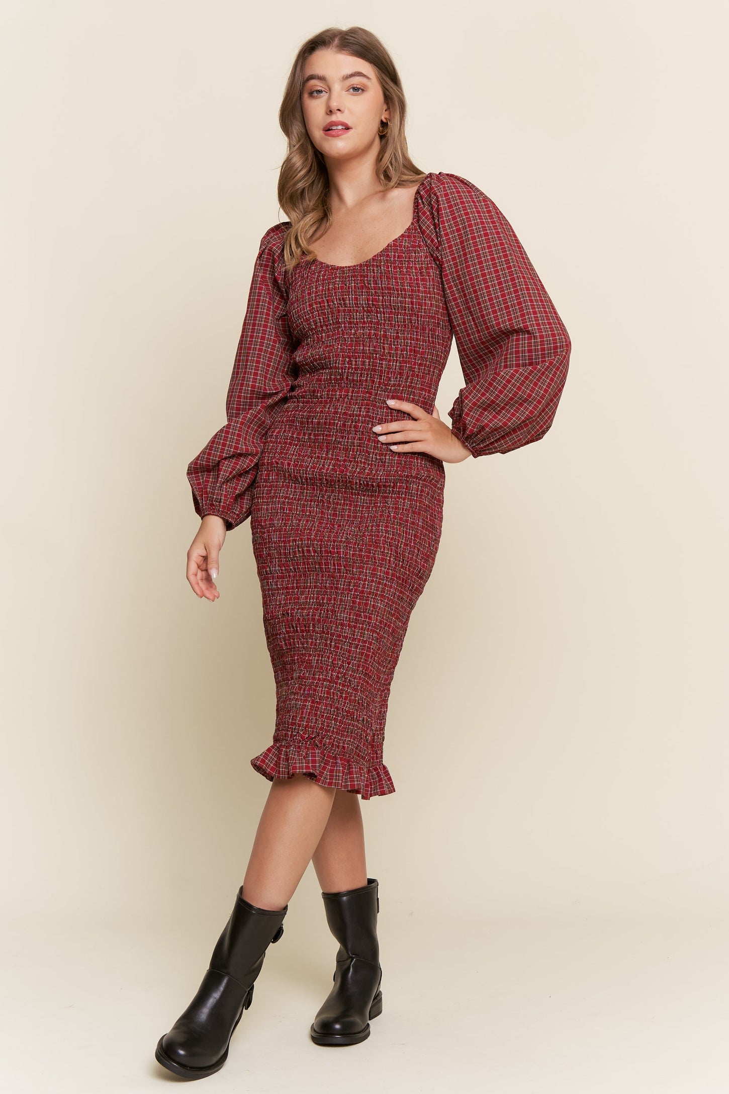 woman wearing a red checkered fitted dress with puffed sleeves and a ruffled hem, paired with black ankle boots