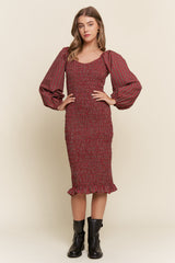 woman wearing a red and black patterned puff sleeve midi dress with a fitted bodice and ruffled hemline