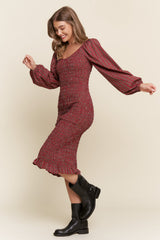 woman wearing a red and black plaid smocked midi dress with puff sleeves and a ruffled hem