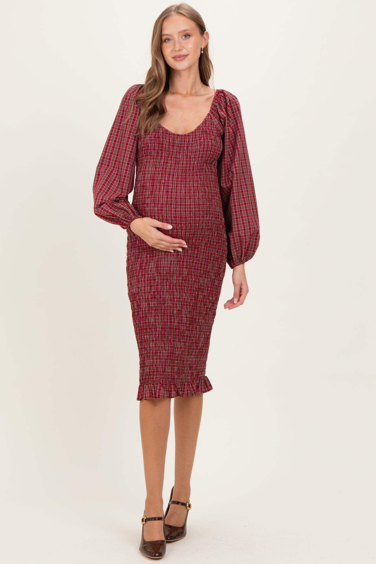 woman wearing a red checkered maternity dress with puffed sleeves and a fitted silhouette, highlighting her baby bump