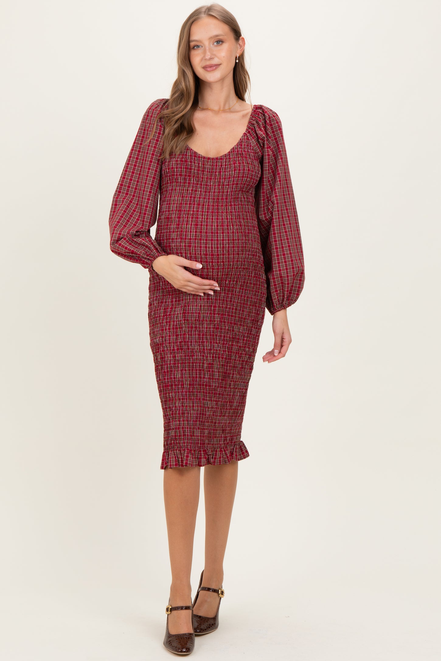woman wearing a red checkered maternity dress with puffed sleeves and a fitted silhouette, highlighting her baby bump