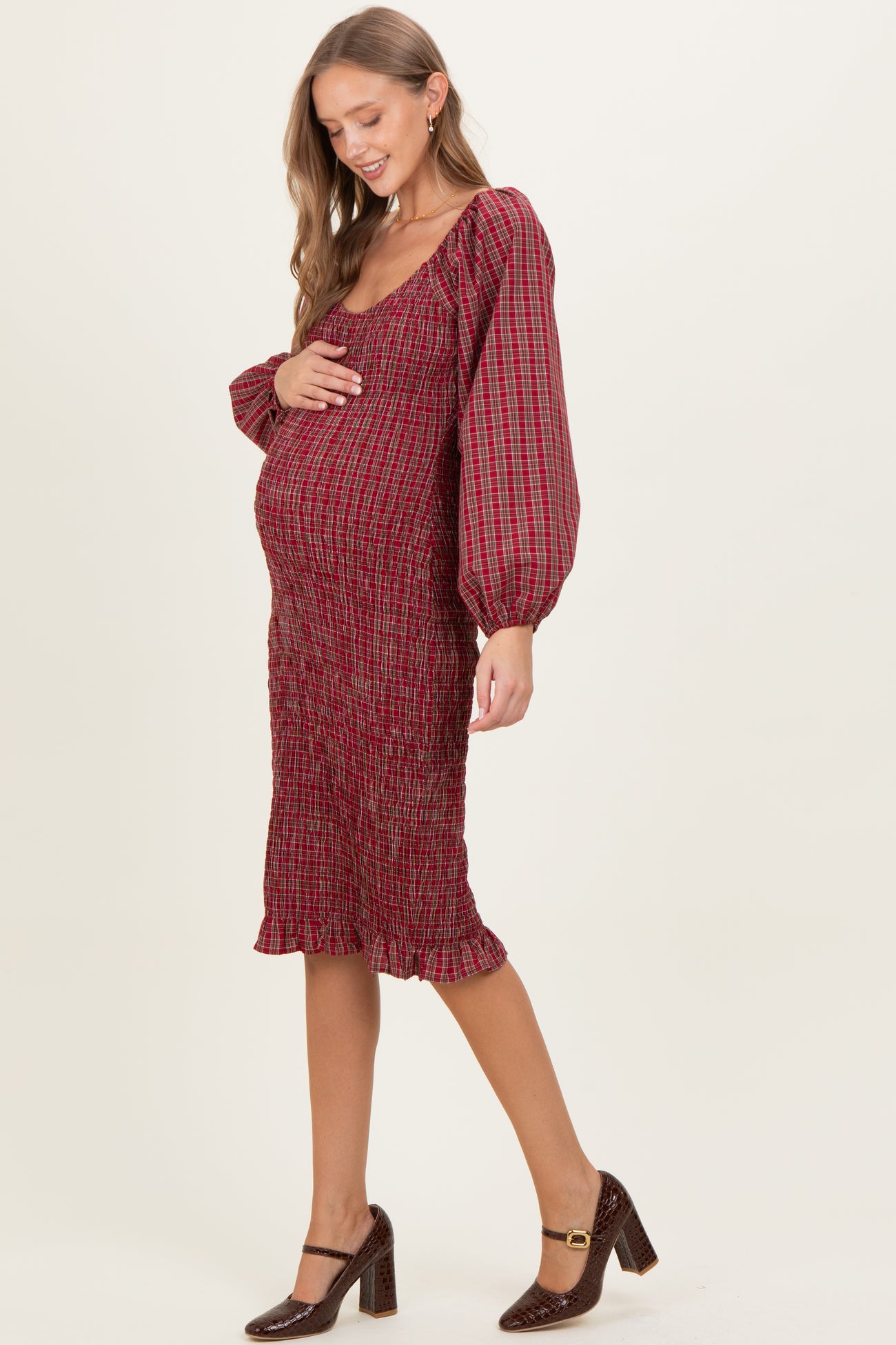 woman wearing a red patterned maternity dress with puff sleeves and holding her baby bump