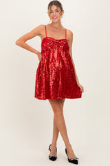woman wearing a red sequin maternity dress with a bow detail and a visible baby bump
