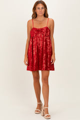 woman wearing a red sequin mini dress with thin straps and a bow detail on the front