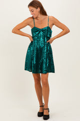 woman wearing a teal sequin mini dress with a bow detail and adjustable spaghetti straps