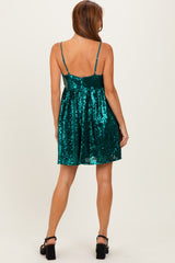 woman wearing a sleeveless teal sequin dress with a flared skirt and spaghetti straps, shown from the back