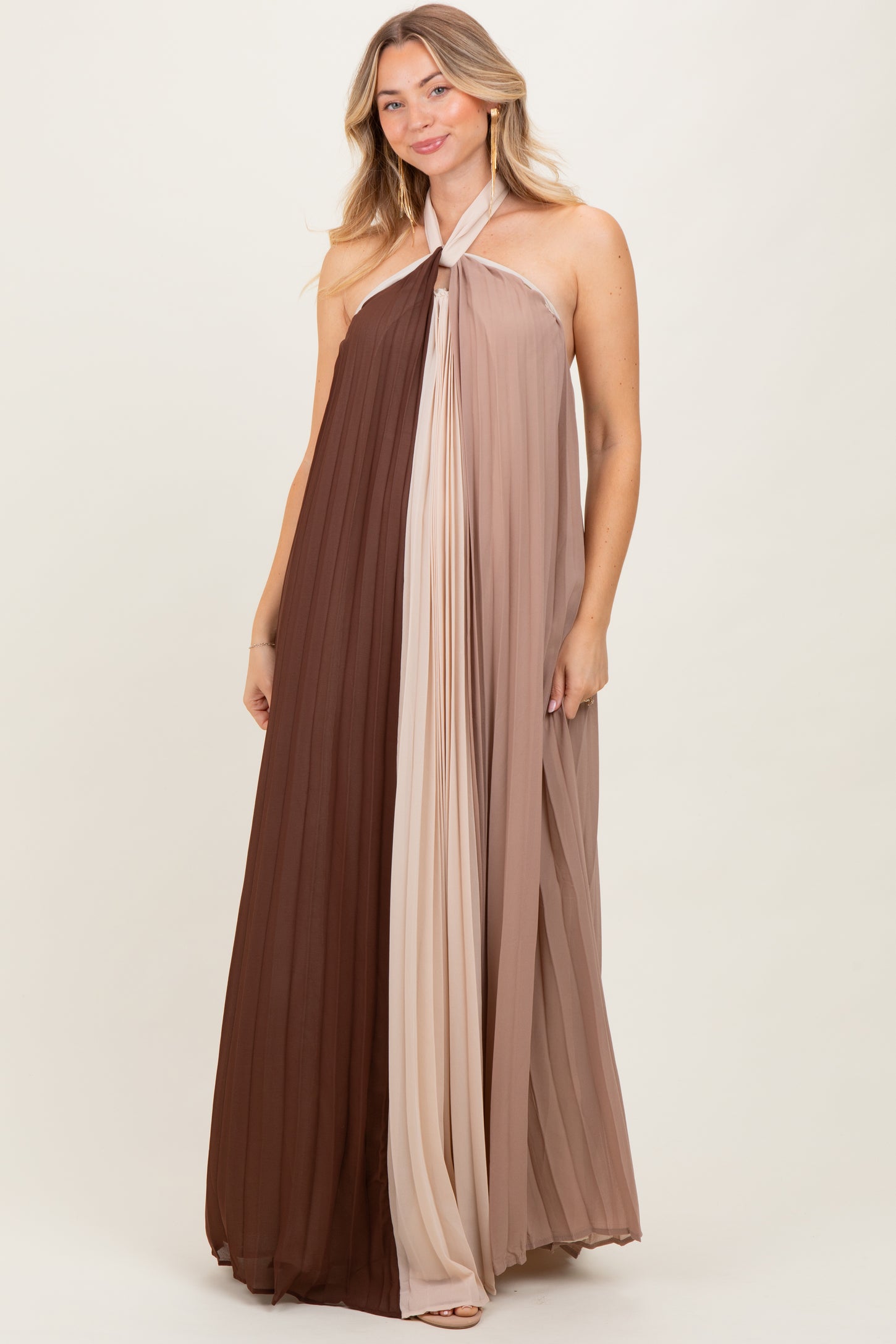 woman wearing a sleeveless color-blocked maxi dress in brown and beige with pleated detailing
