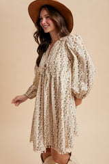 woman wearing a cream floral print puff sleeve dress with a drawstring waist and a wide-brimmed hat