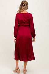 woman wearing a burgundy maternity dress with long sleeves and pleated skirt, showing the back view