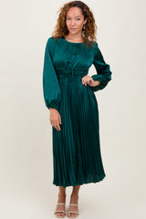 woman wearing a teal satin pleated midi dress with long sleeves and a smocked waistline