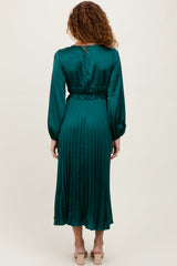 woman wearing a long sleeve emerald green pleated dress with a cinched waist, viewed from the back