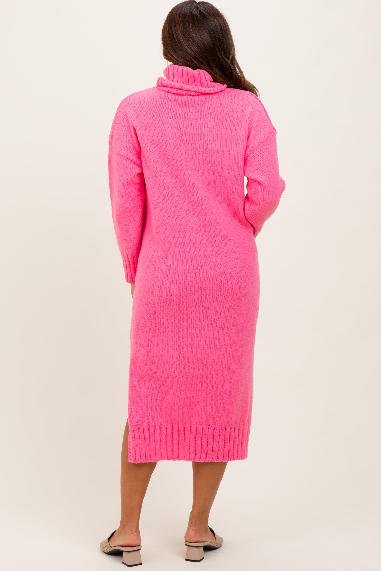 woman wearing a pink long sleeve maternity sweater dress with a turtleneck and a ribbed hem