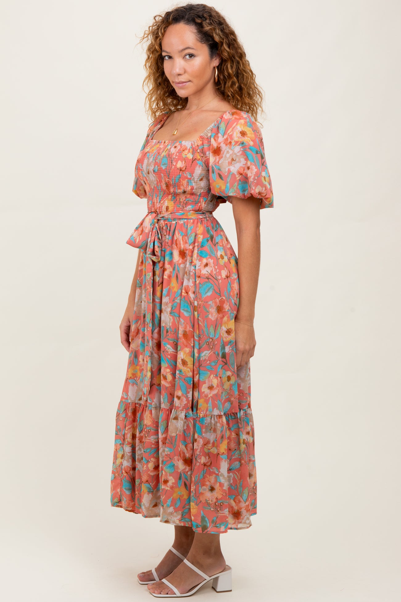 woman wearing a floral midi dress with puff sleeves and a cinched waist, standing against a neutral background