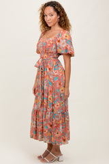 woman wearing a floral midi dress with puff sleeves and a cinched waist, standing against a neutral background