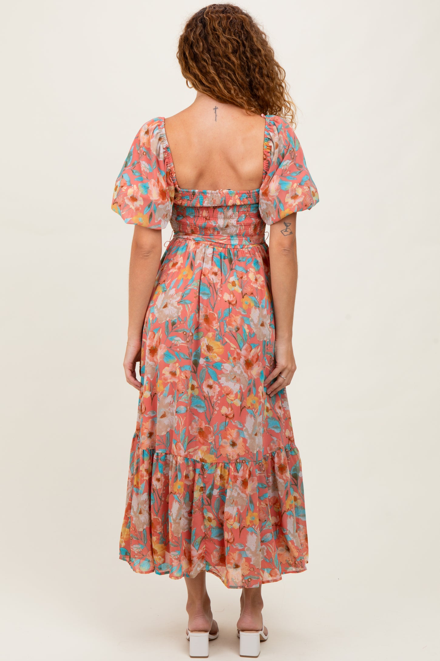 woman wearing a floral midi dress with puff sleeves and a smocked bodice, shown from the back