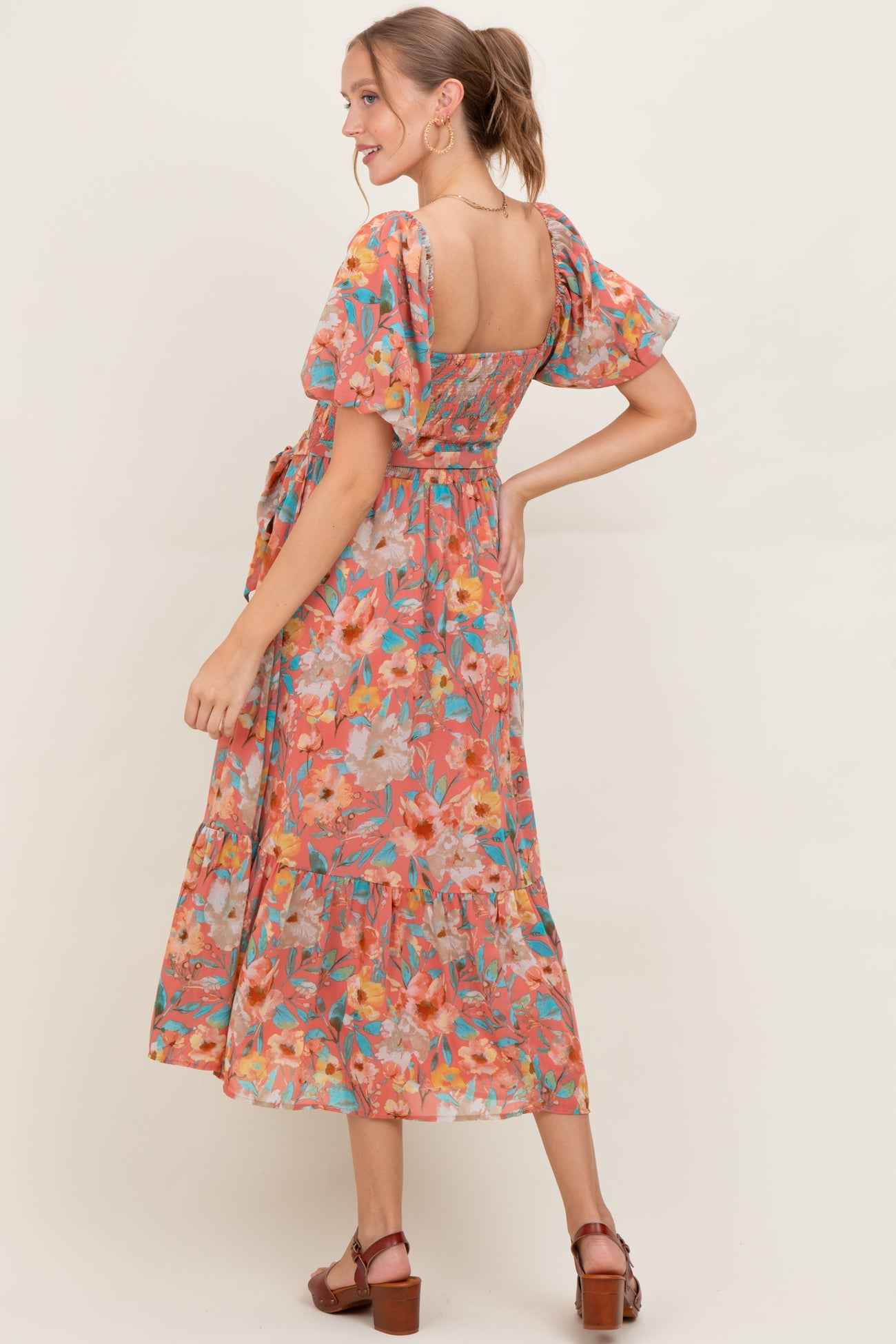 woman wearing a floral maternity dress with puff sleeves and a tiered skirt, showing the back view