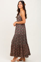 woman wearing a sleeveless dark floral maxi dress with a tiered skirt and smiling to the side
