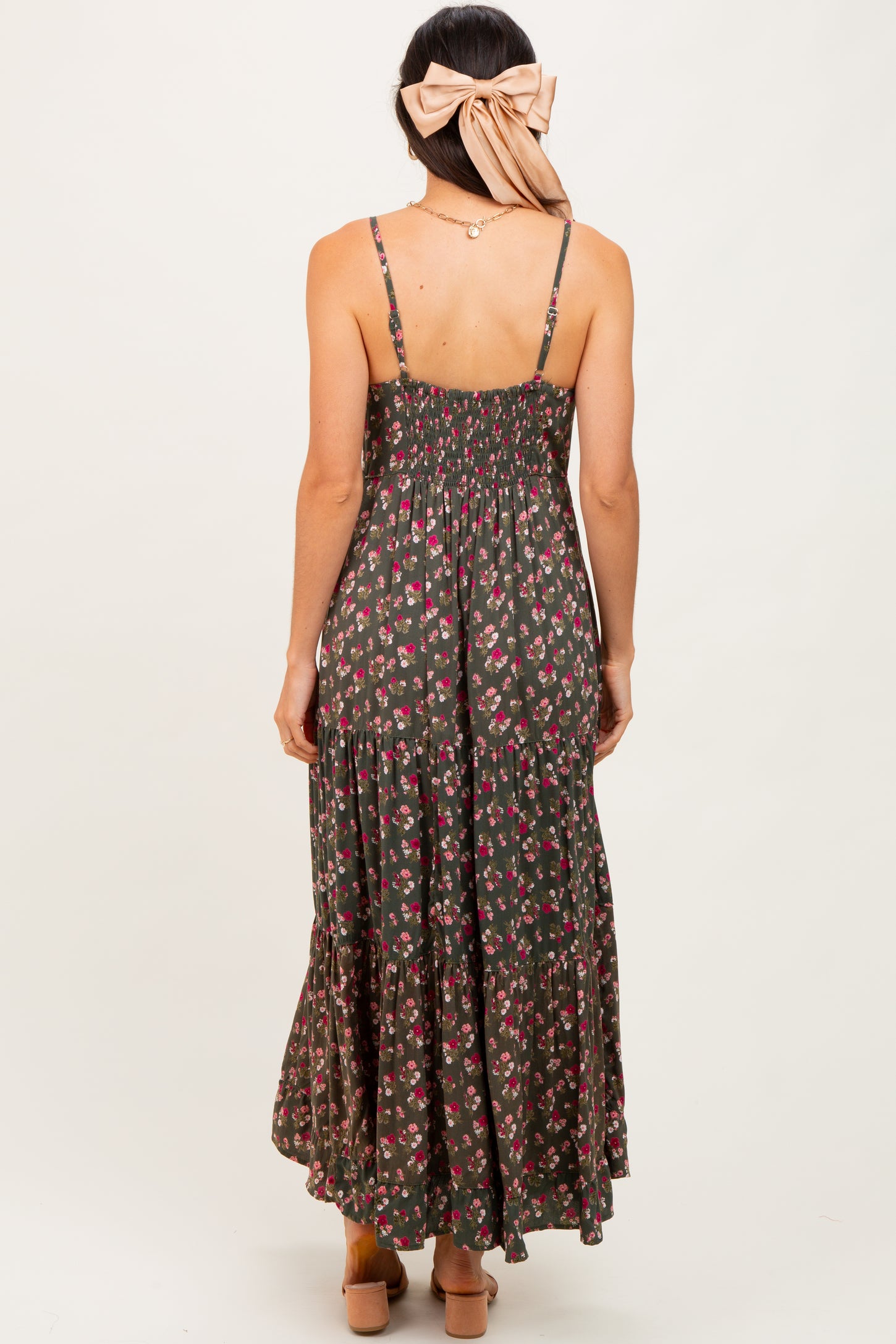 woman wearing a dark green floral maxi dress with smocked bodice and tiered skirt, seen from the back
