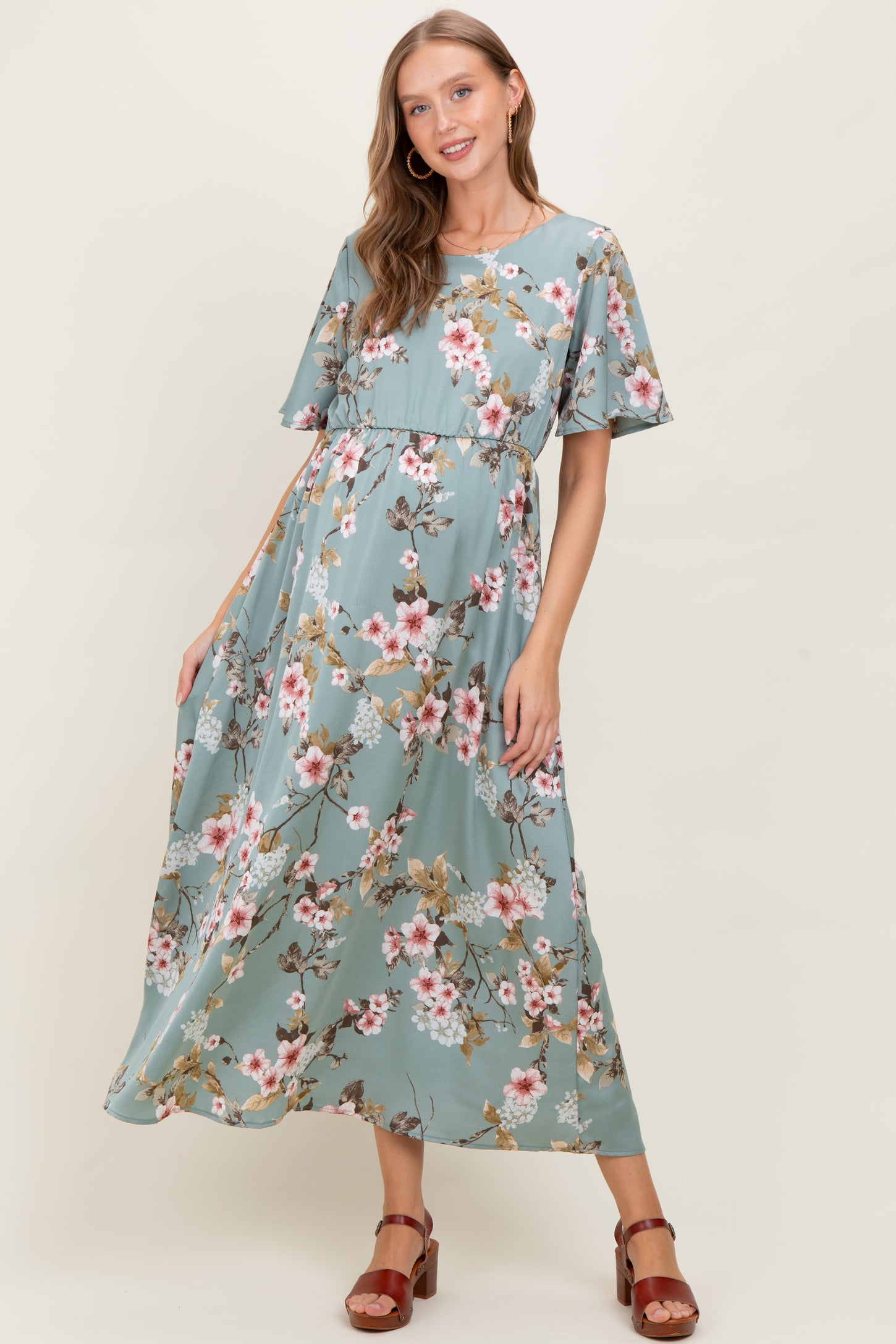 woman wearing a floral maternity maxi dress with short flared sleeves and a cinched waist