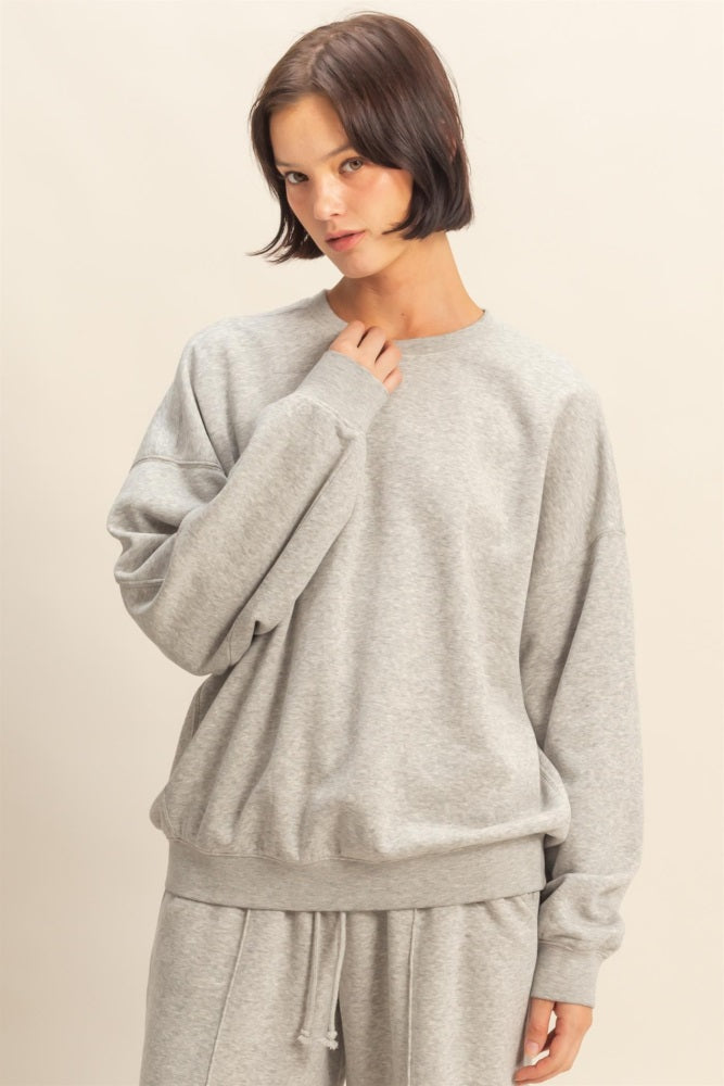 woman wearing a gray oversized sweatshirt with a crew neckline and relaxed fit