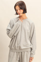 woman wearing a gray oversized sweatshirt with a crew neckline and relaxed fit