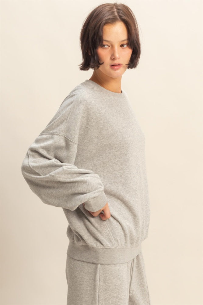 woman wearing a grey oversized sweatshirt with long sleeves and a relaxed fit