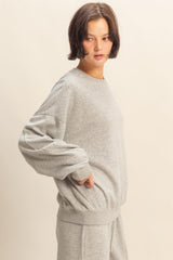 woman wearing a grey oversized sweatshirt with long sleeves and a relaxed fit