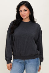 woman wearing a dark gray oversized sweatshirt with long sleeves and a relaxed fit, paired with light blue jeans