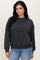 woman wearing a dark gray oversized sweatshirt with long sleeves and a relaxed fit, paired with light blue jeans