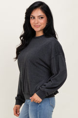 woman wearing a dark gray cropped sweatshirt with a relaxed fit and long sleeves, standing and smiling