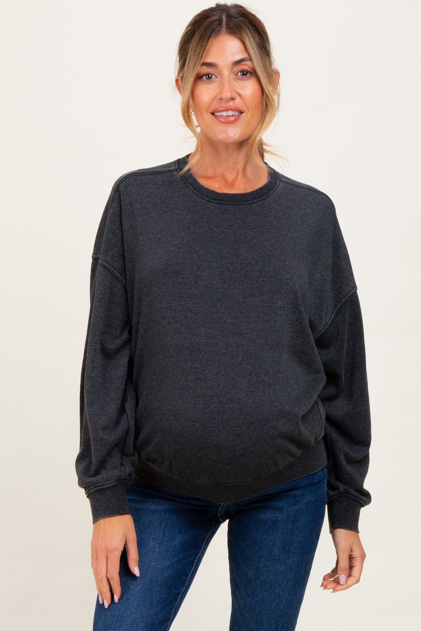 woman wearing a dark grey oversized maternity sweatshirt and showing her baby bump